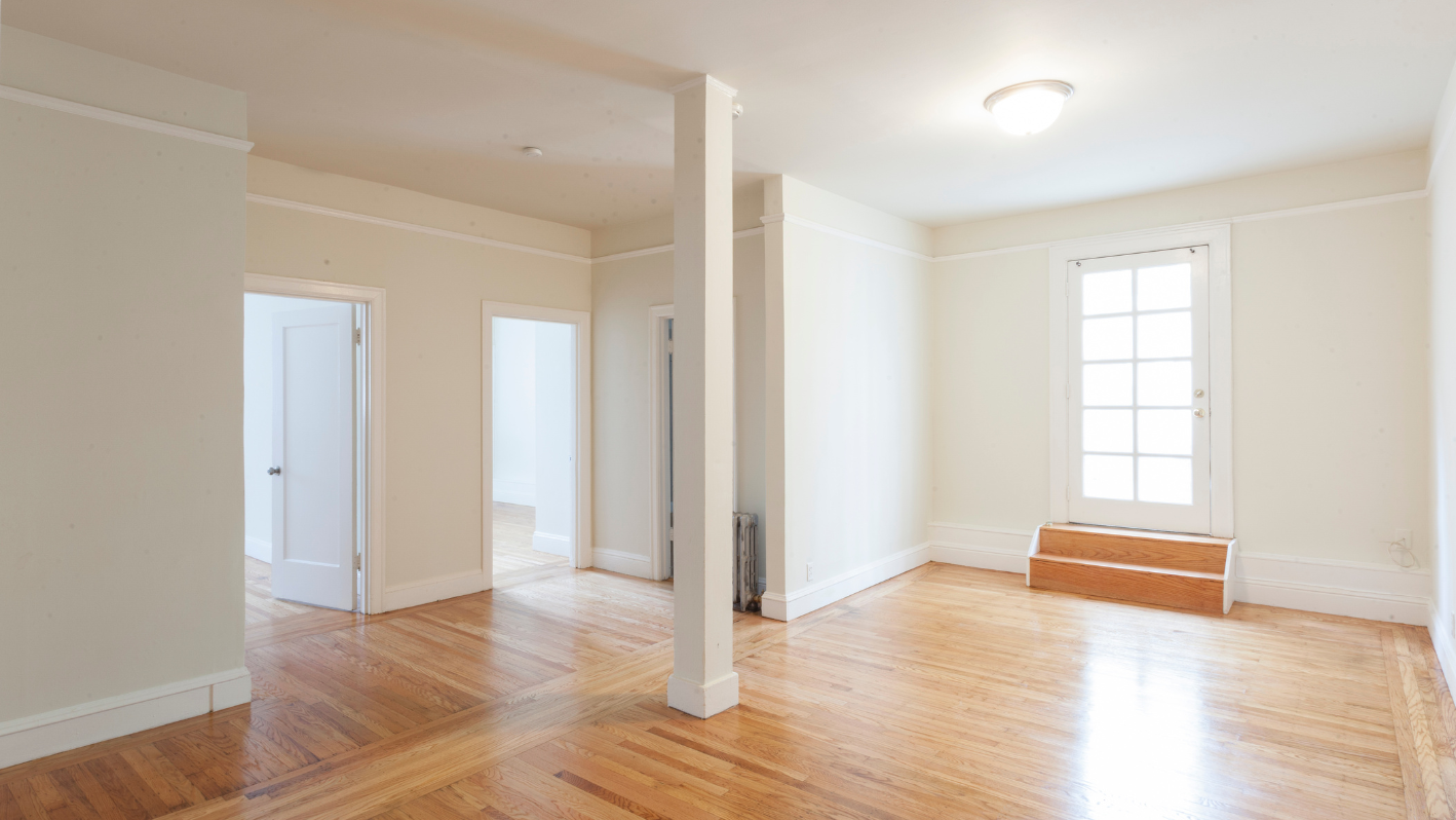 An empty room with hard wood floors and white walls